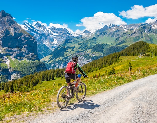 Cyclists on a mountain trail with views of Grindelwald First, Switzerland.