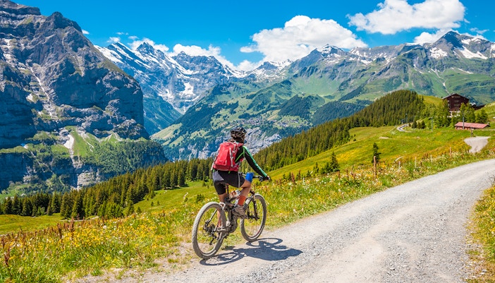 Cyclists on a mountain trail with views of Grindelwald First, Switzerland.