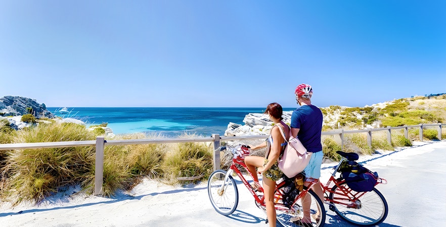 Couple on bikes overlooking the ocean on Rottnest Island, part of the ferry and adventure boat tour.