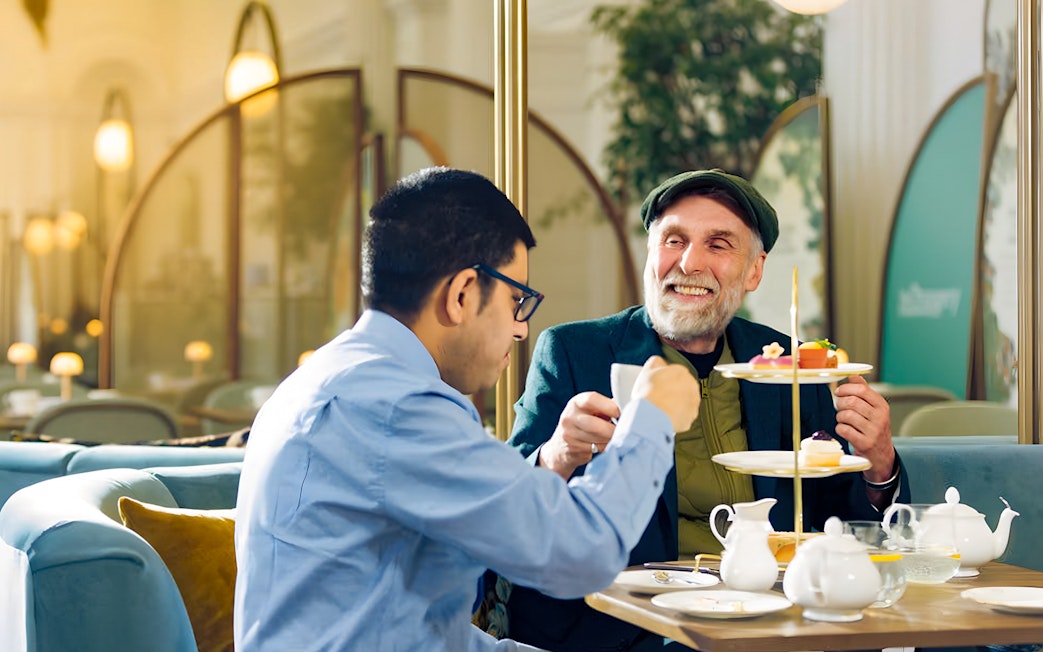 Guests enjoying afternoon tea at Kensington Palace with a tiered tray of pastries.