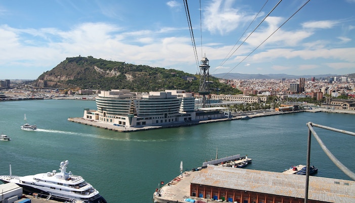 Montjuic Cable Car over Barcelona cityscape with Aquarium Barcelona in view.