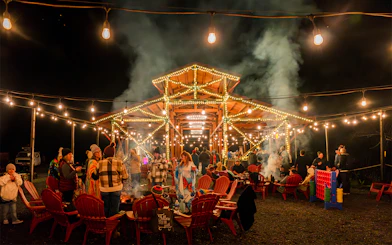 Outdoor gathering at Glen Blair Bar, San Francisco, with people around a fire pit under string lights.