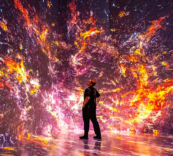 Person observing immersive digital art installation at ARTECHOUSE, New York.