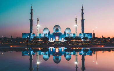 Sheikh Zayed Grand Mosque at sunset, Abu Dhabi, reflecting in water.