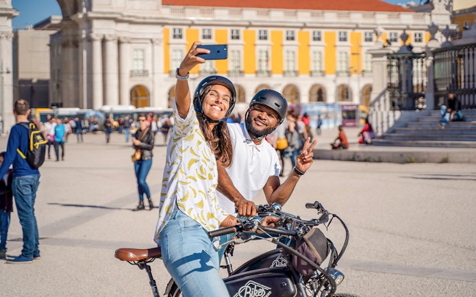 Couple taking a selfie on bikes at Commerce Square, Lisbon.