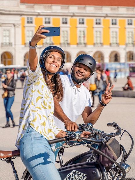 Couple taking a selfie on bikes at Commerce Square, Lisbon.