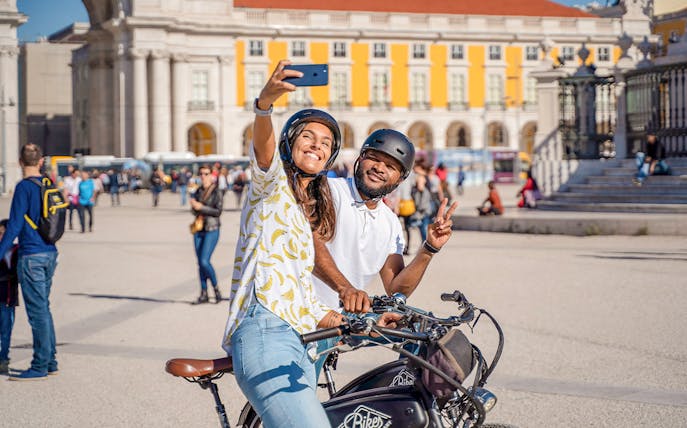 Couple taking a selfie on bikes at Commerce Square, Lisbon.