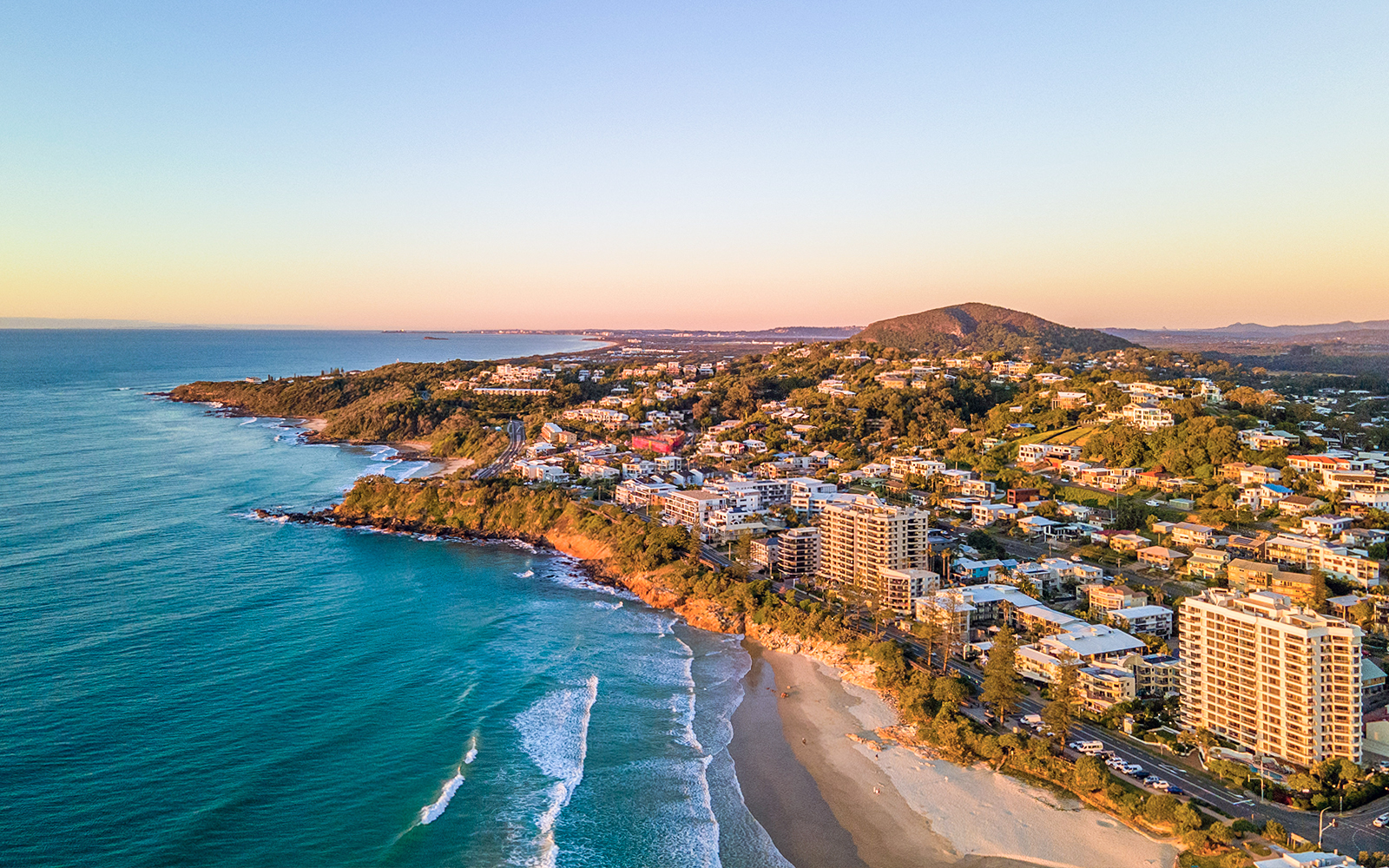 Sunshine Coast beach with people enjoying the ocean and coastal scenery.