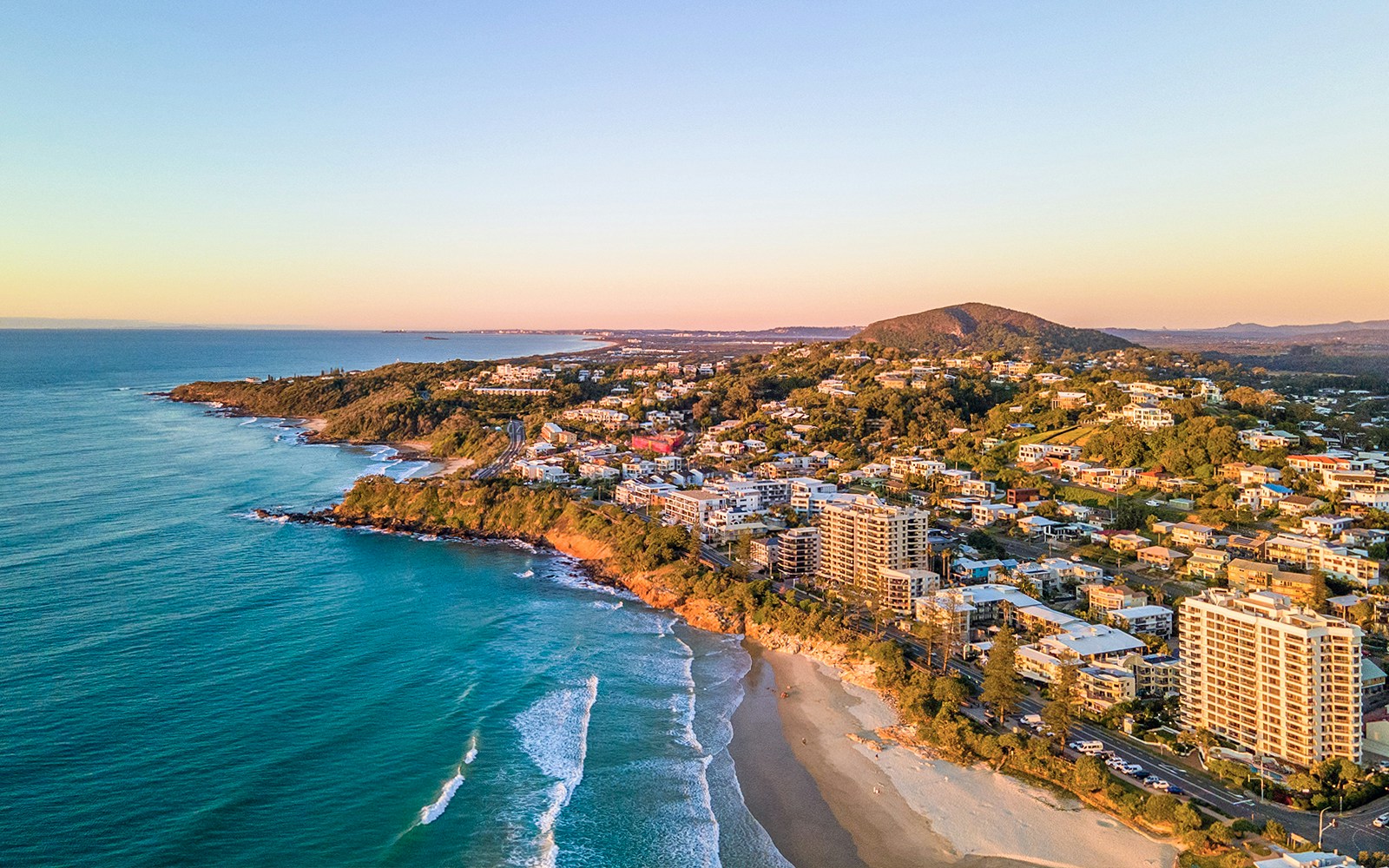 Sunshine Coast beach with people enjoying the ocean and coastal scenery.