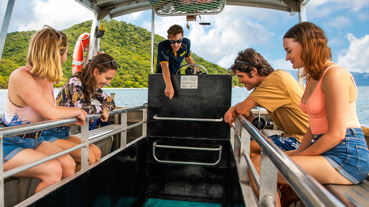 Tourists on a glass-bottom boat tour at Fitzroy Island, viewing marine life.