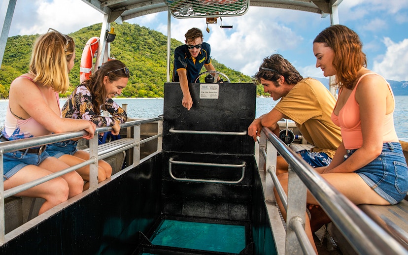 Tourists on a glass-bottom boat tour at Fitzroy Island, viewing marine life.