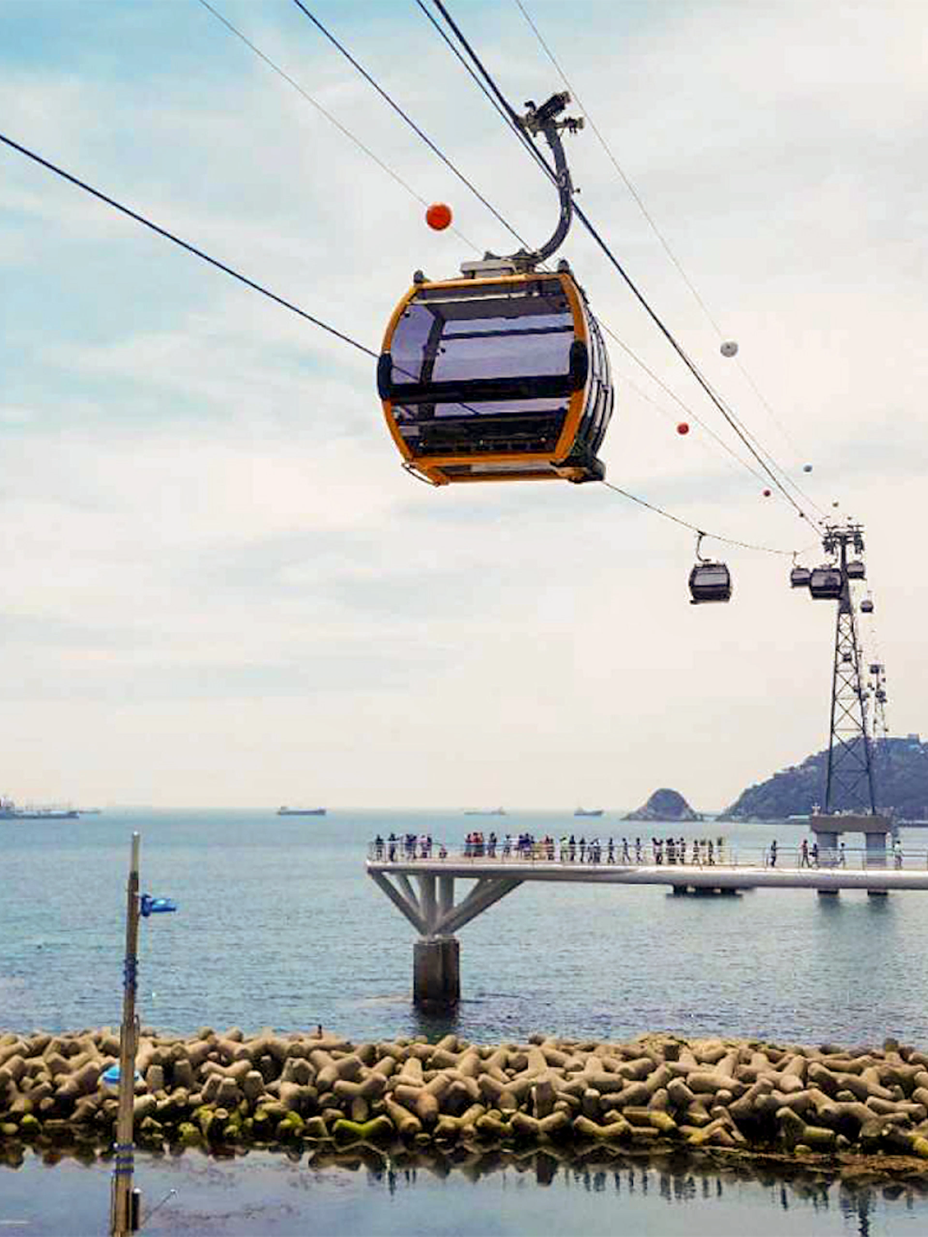 Cable car over Songdo Beach in Busan with ocean view and distant ships.