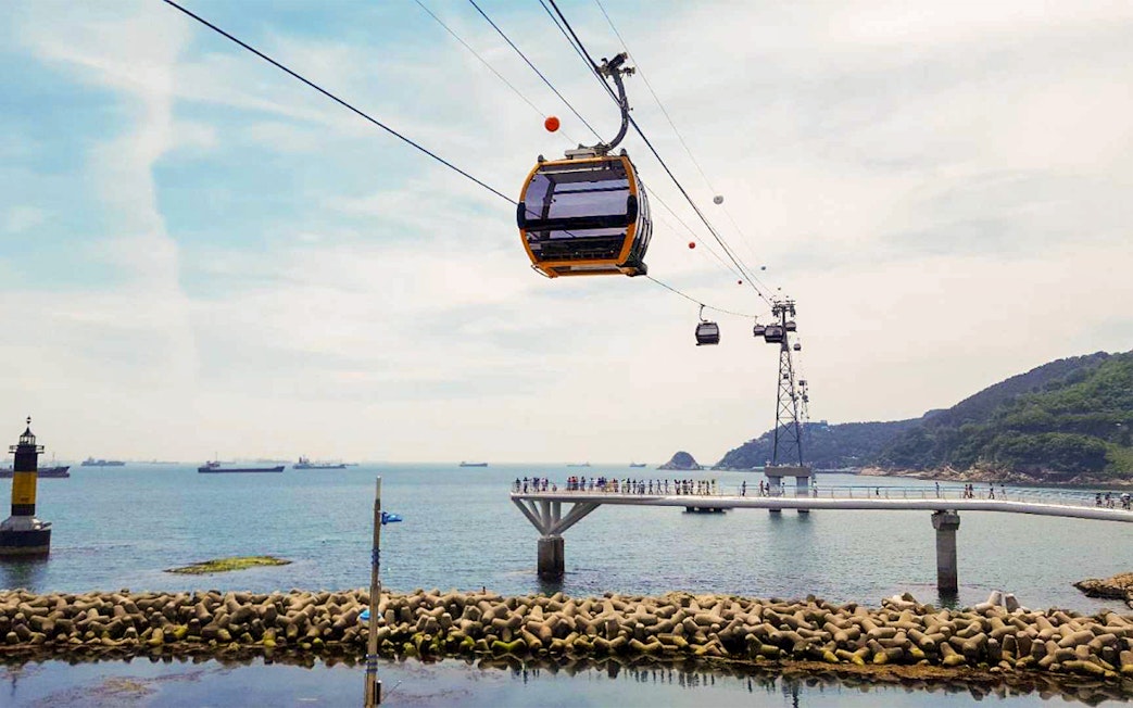 Cable car over Songdo Beach in Busan with ocean view and distant ships.