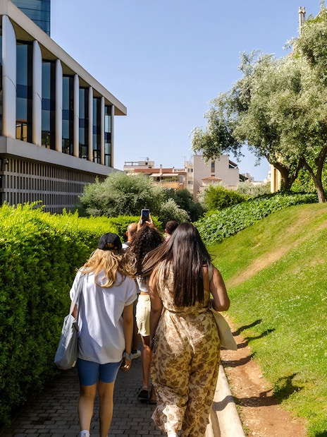 Tourists walking towards Acropolis Museum, Athens, surrounded by greenery.