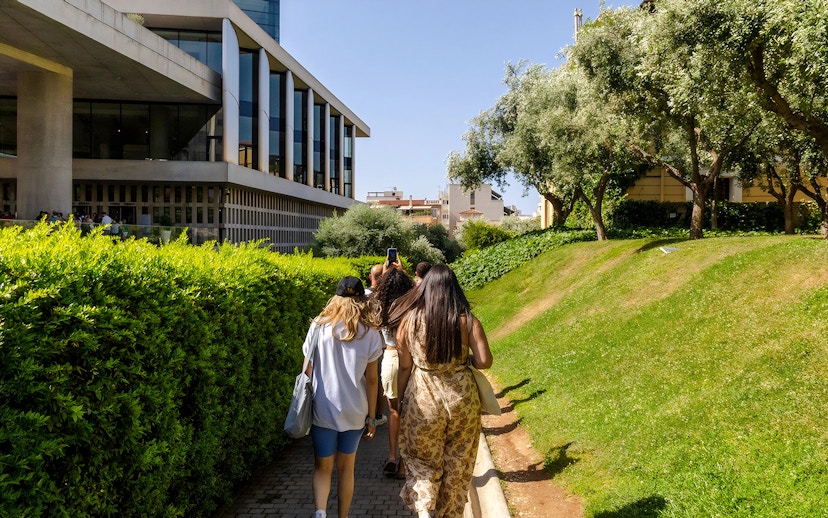 Tourists walking towards Acropolis Museum, Athens, surrounded by greenery.