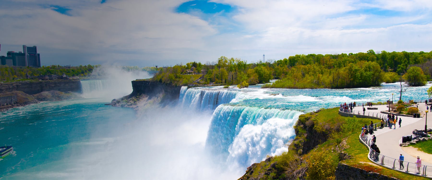 Niagara Falls view from Canadian side with tourists on observation path.