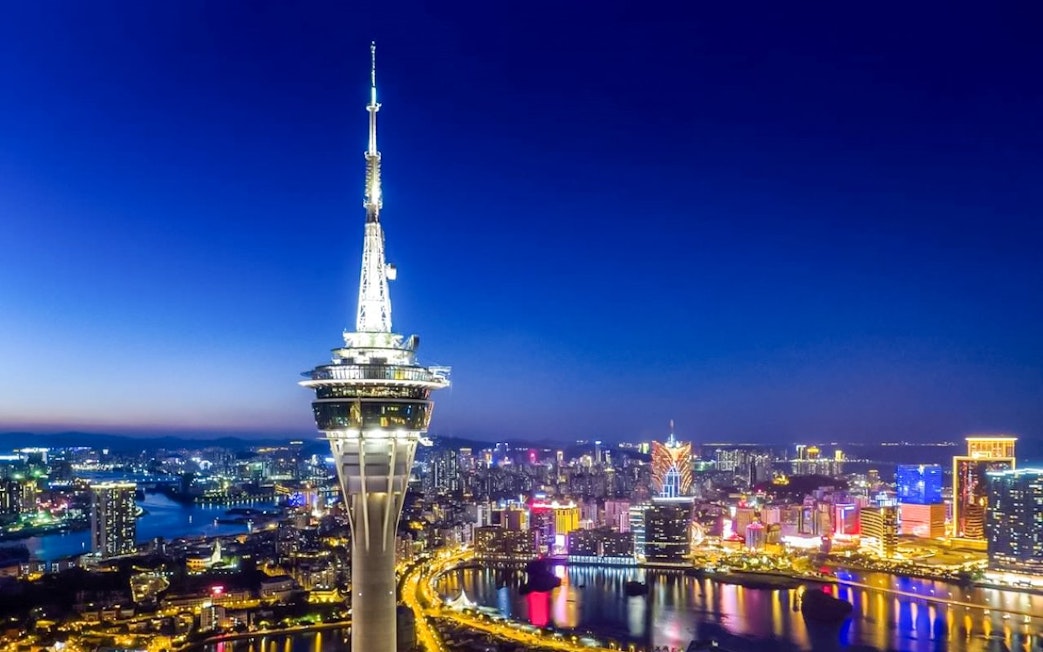 Macau Tower illuminated at night with city skyline in the background.