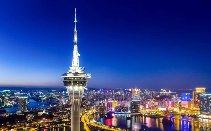 Macau Tower illuminated at night with city skyline in the background.