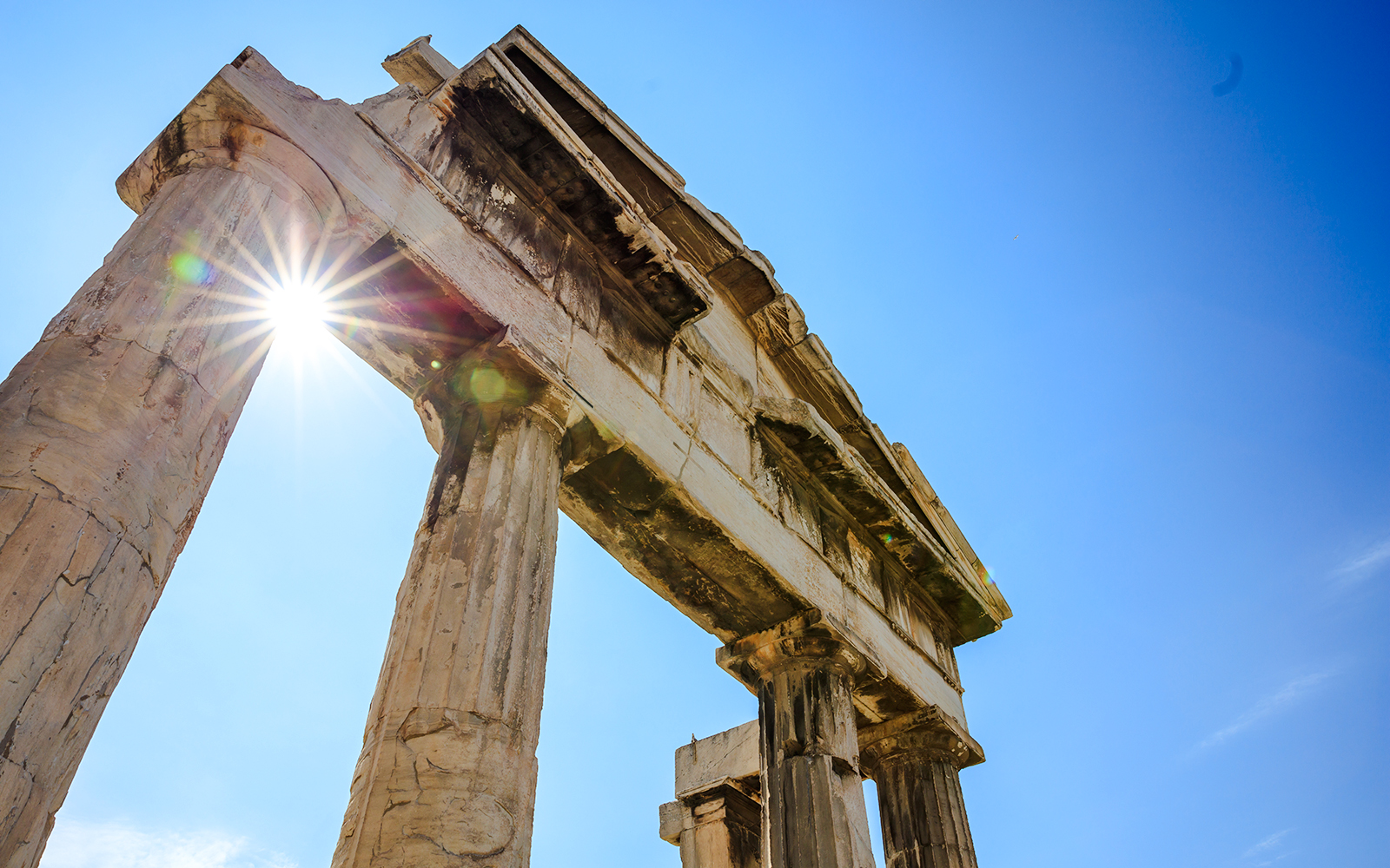 Ancient columns of the Roman Agora in Athens, Greece, with sunlight peeking through.