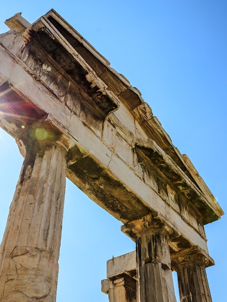 Ancient columns of the Roman Agora in Athens, Greece, with sunlight peeking through.