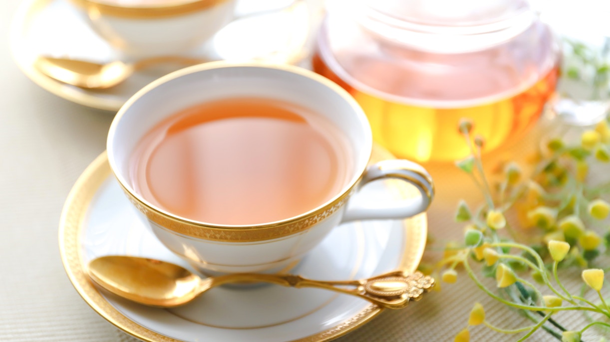 English afternoon tea with a cup of tea, gold-trimmed saucer, and spoon.