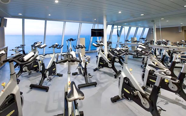 Cruise ship gym with stationary bikes overlooking the ocean.