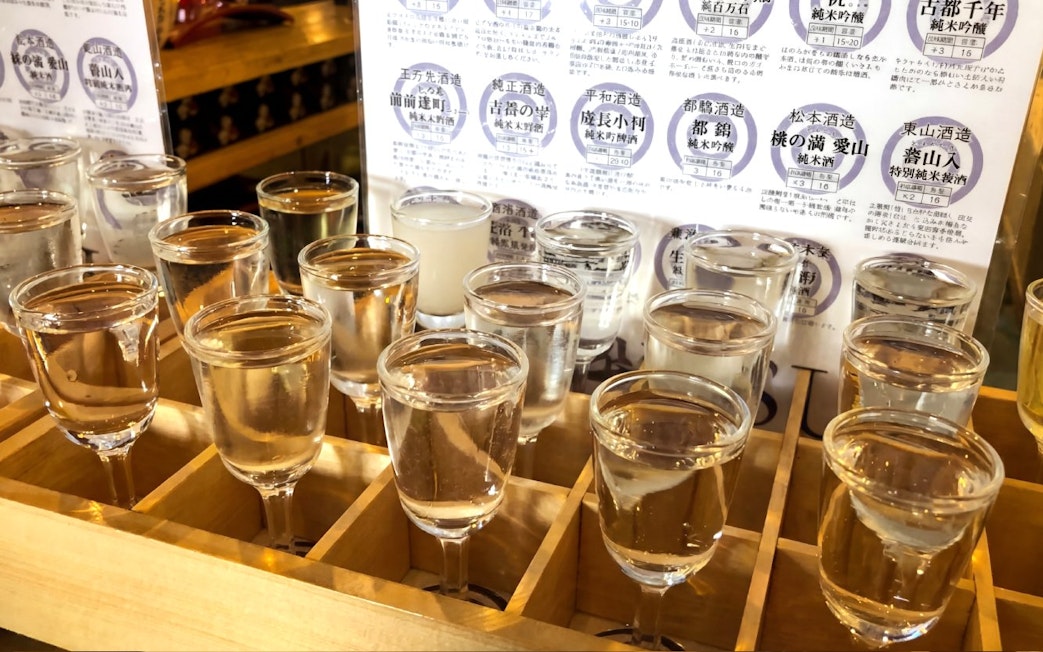 Sake tasting glasses arranged on a wooden tray at a Kyoto brewery tour.