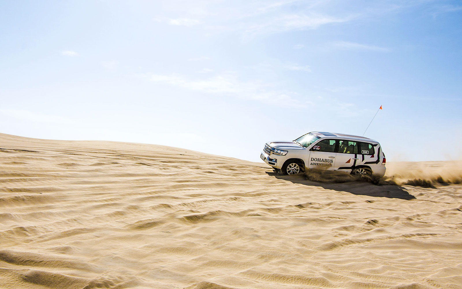 SUV driving through sand dunes on a desert safari in Doha.