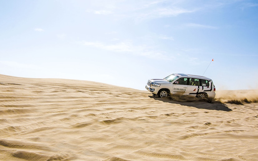 SUV driving through sand dunes on a desert safari in Doha.