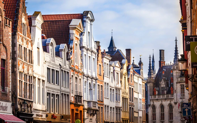 Historic buildings along Steenstraat in Bruges, Belgium, with ornate facades and spires.