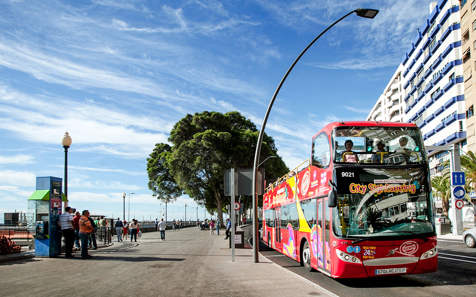 Santa Cruz hop-on hop-off bus on a city street with tourists on board.