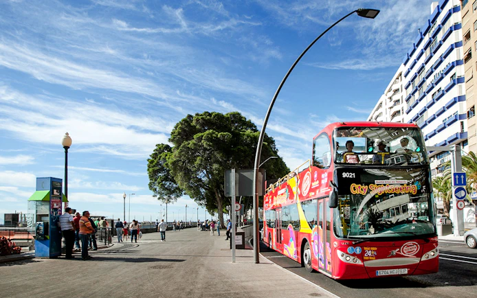 Santa Cruz hop-on hop-off bus on a city street with tourists on board.
