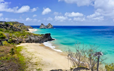 Sancho Beach view with turquoise waters and Dois Irmãos rocks, Noronha Island tour.