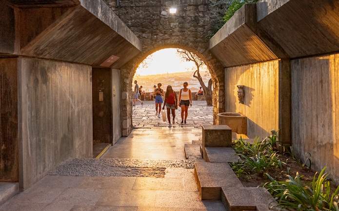 Visitors walking through an archway at St George's Castle during sunset.