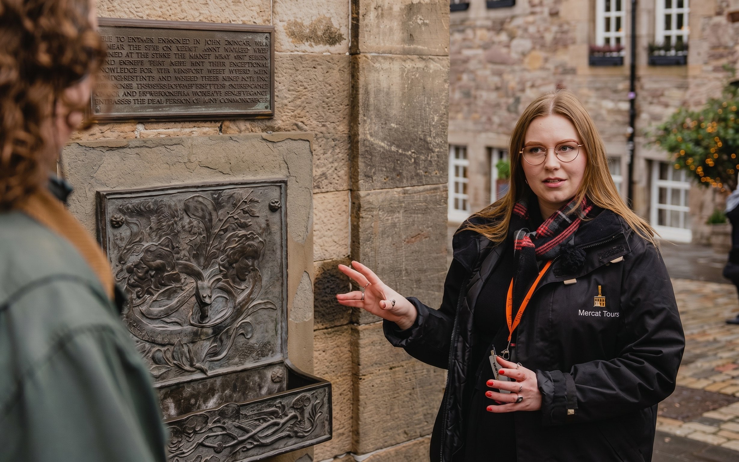 Tour guide explaining a historical plaque related to the Witches of Edinburgh.