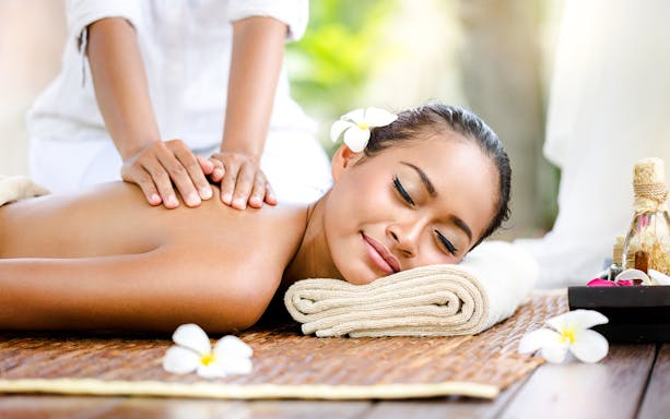 Massage therapy at a spa in Bali with frangipani flowers and essential oils.