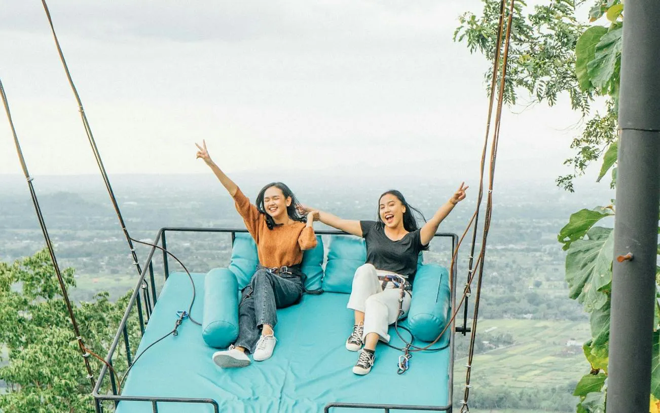 Two people enjoying a scenic swing ride with a view of Dubai landscape.