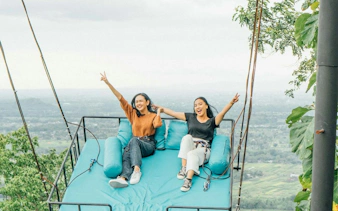 Two people enjoying a scenic swing ride with a view of Dubai landscape.