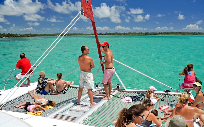Catamaran with tourists sailing to Ile aux Cerf, Mauritius, enjoying the sun and sea.