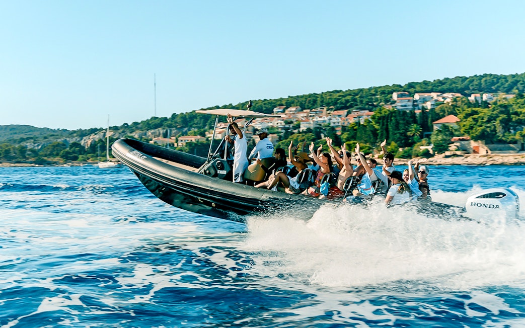 Guests enjoying a speedboat ride near a coastal town with lush greenery.