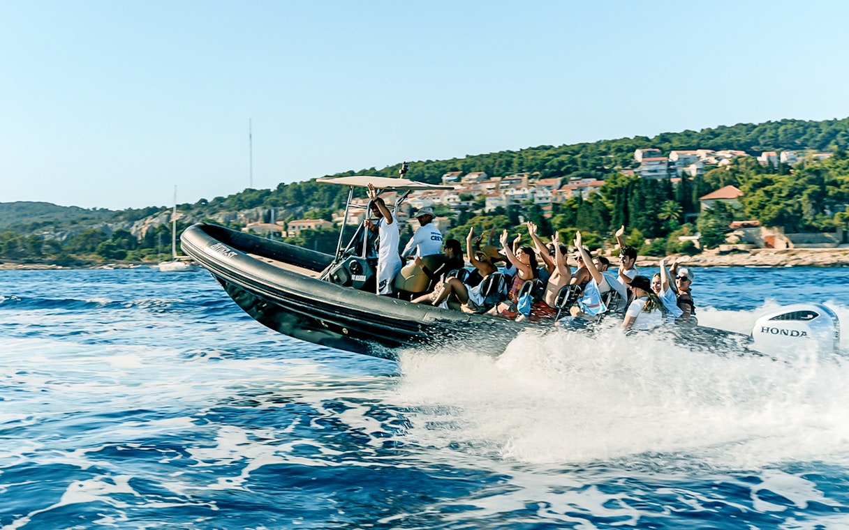 Guests enjoying a speedboat ride near a coastal town with lush greenery.