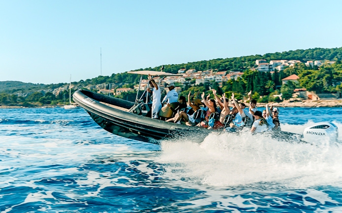 Guests enjoying a speedboat ride near a coastal town with lush greenery.