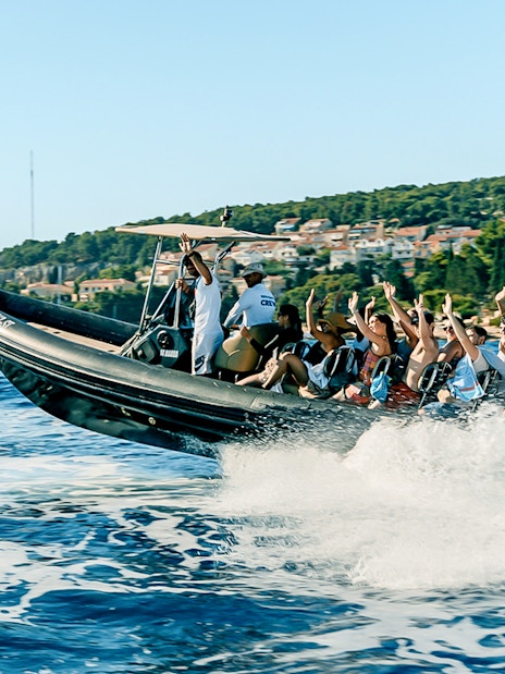 Guests enjoying a speedboat ride near a coastal town with lush greenery.