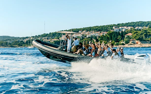 Guests enjoying a speedboat ride near a coastal town with lush greenery.