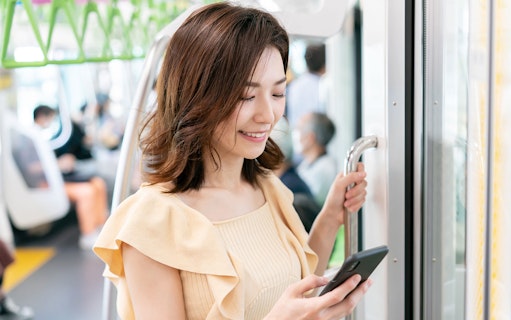 Person using smartphone on a train in Japan, illustrating WiFi rental service.