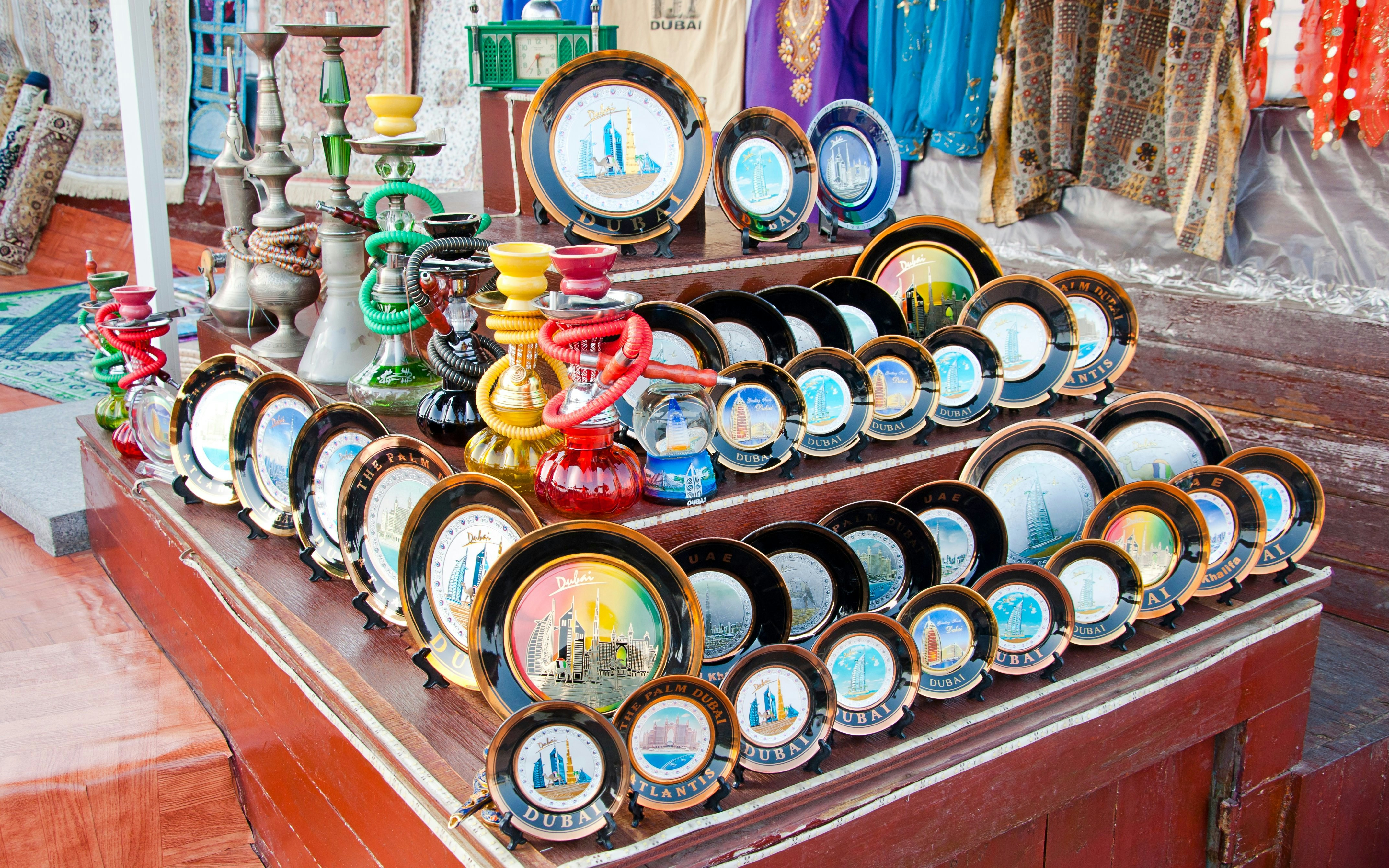Dubai souvenir plates and hookahs displayed at a market stall in the United Arab Emirates.