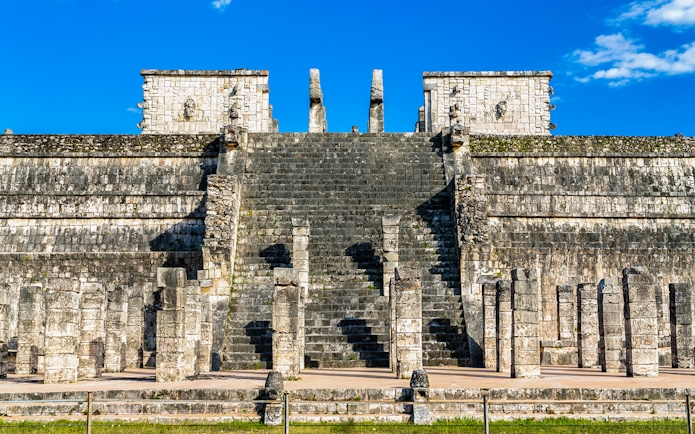 Temple of the Warriors steps and columns at Chichen Itza under a clear blue sky.