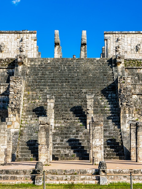 Temple of the Warriors steps and columns at Chichen Itza under a clear blue sky.