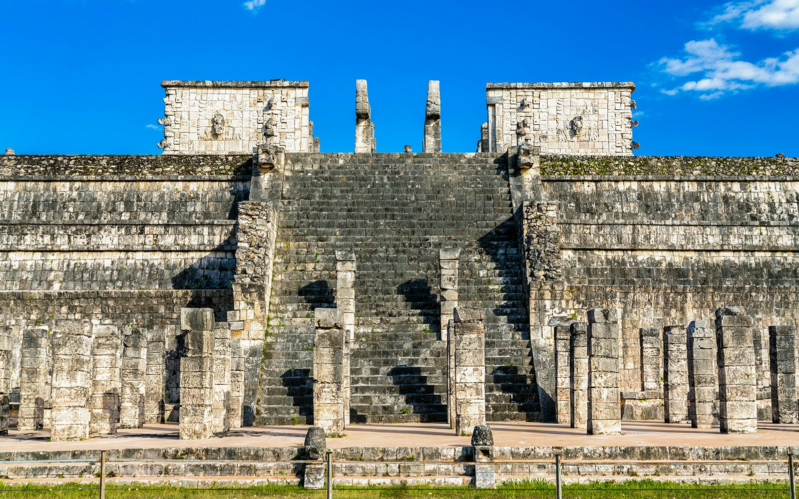 Temple of the Warriors steps and columns at Chichen Itza under a clear blue sky.