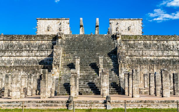 Temple of the Warriors steps and columns at Chichen Itza under a clear blue sky.